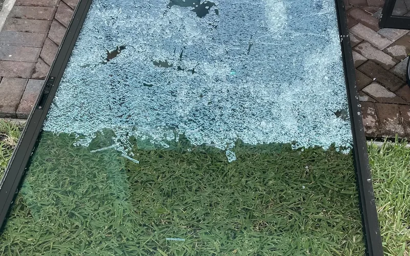 Shattered sliding door glass panel removed before a new pane is fitted