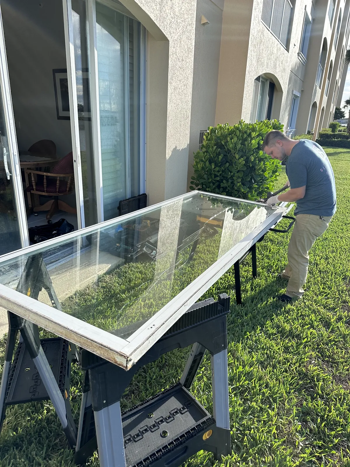 SliderPro technician working on a sliding glass door panel lifted out onto sawhorses