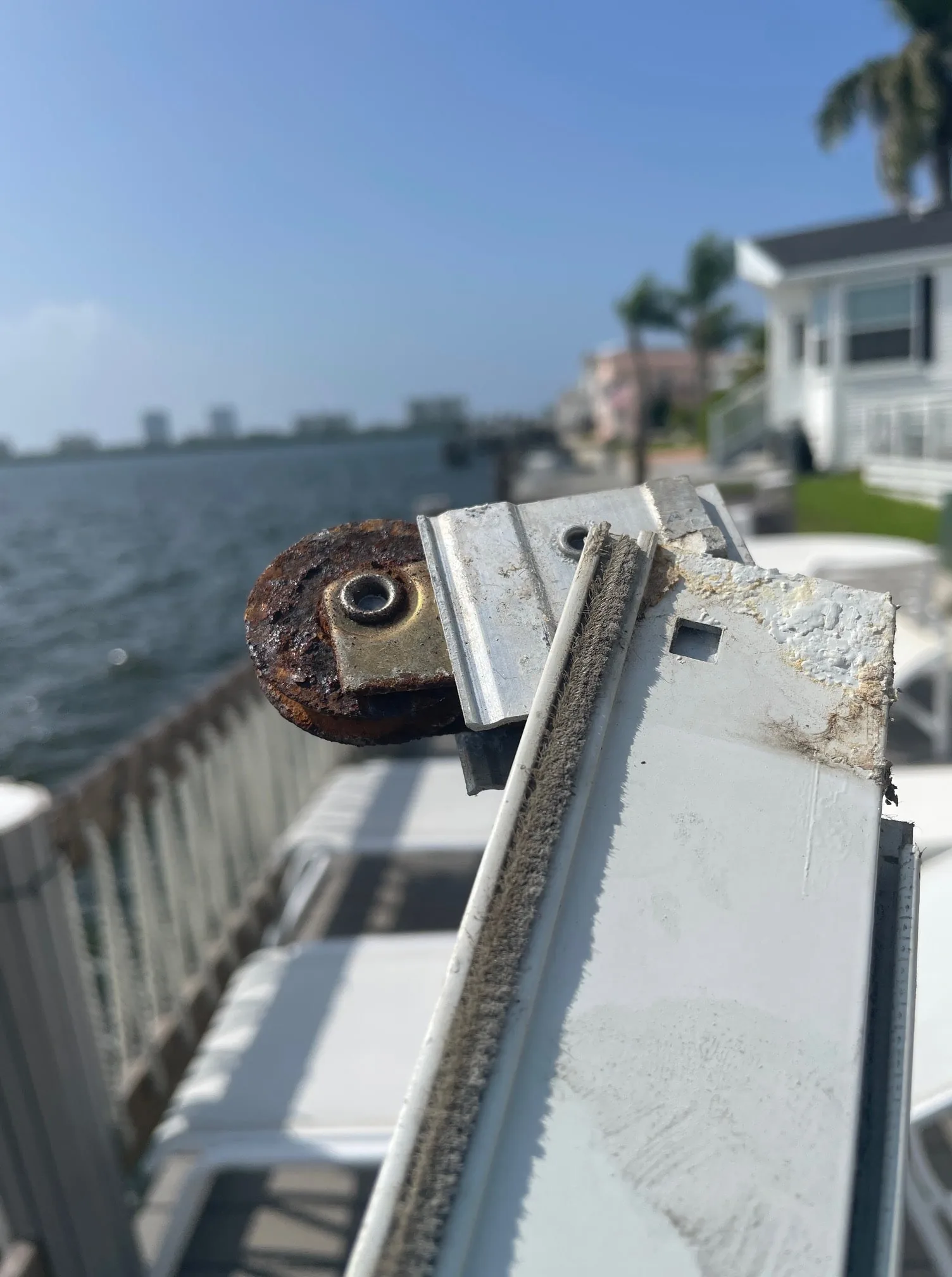 Corroded sliding glass door roller on a worn track before replacement