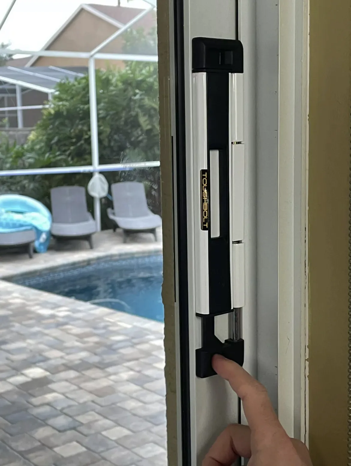 Heavy-duty deadbolt security lock installed on a sliding patio door by a pool