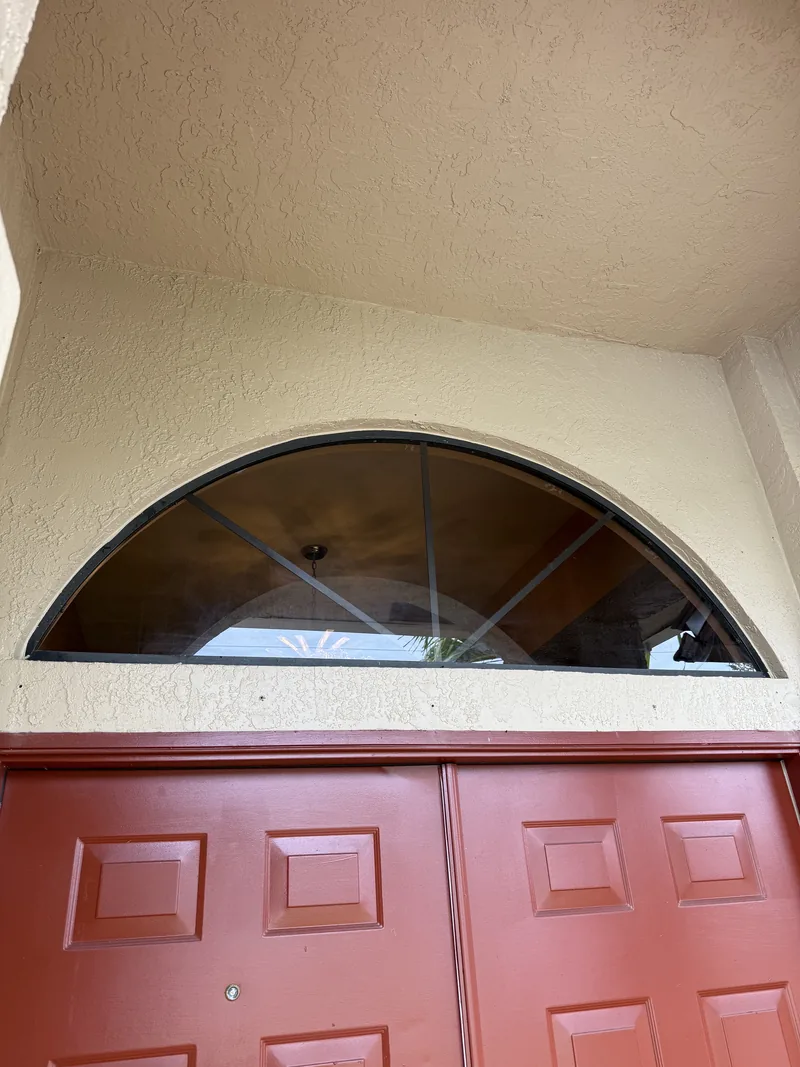 Completed half-round transom with new bronze glass and radial muntin bars seated in the original stucco opening